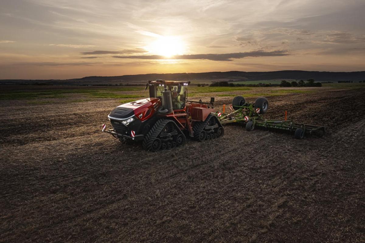 Red tractor on a field with a sunset behind it