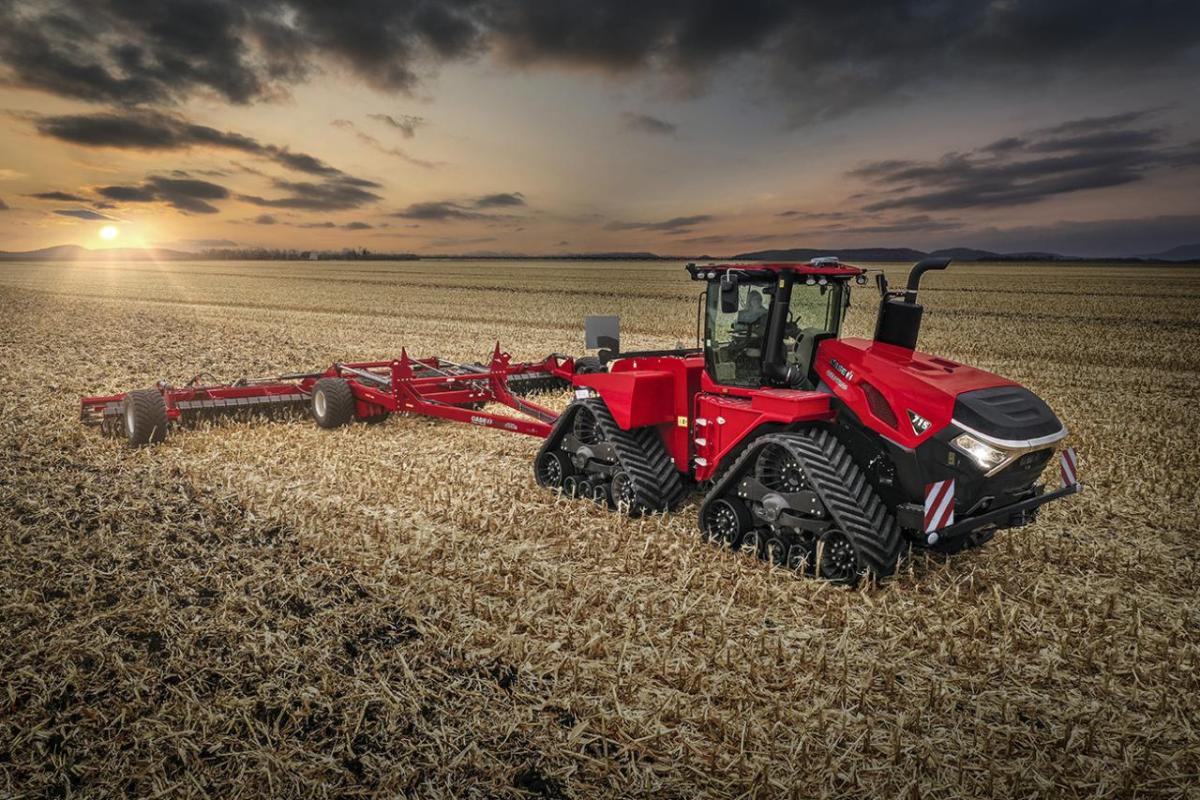 Red tractor on a field with a sunset behind it