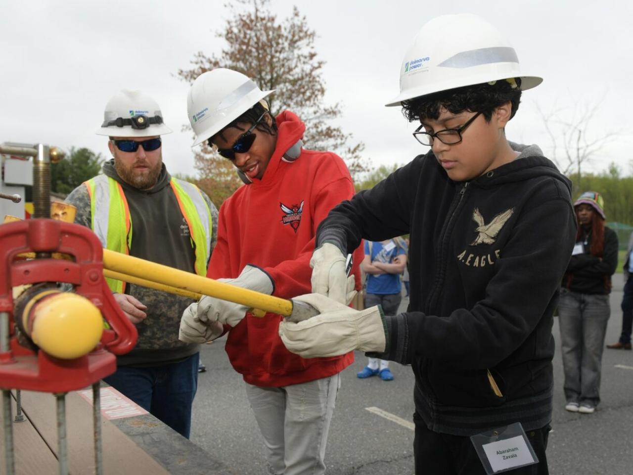 students in hard hats working on equipment outside